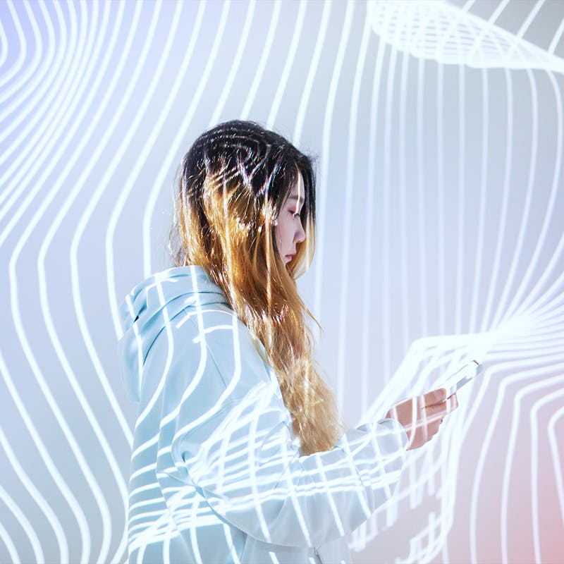 Woman using mobile phone in the holographic background