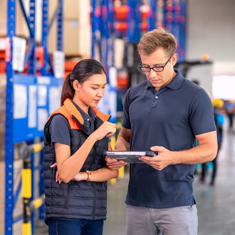 Two people on a warehouse working on a tablet