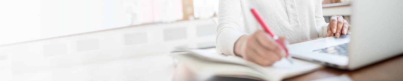Close up of woman writing and using laptop